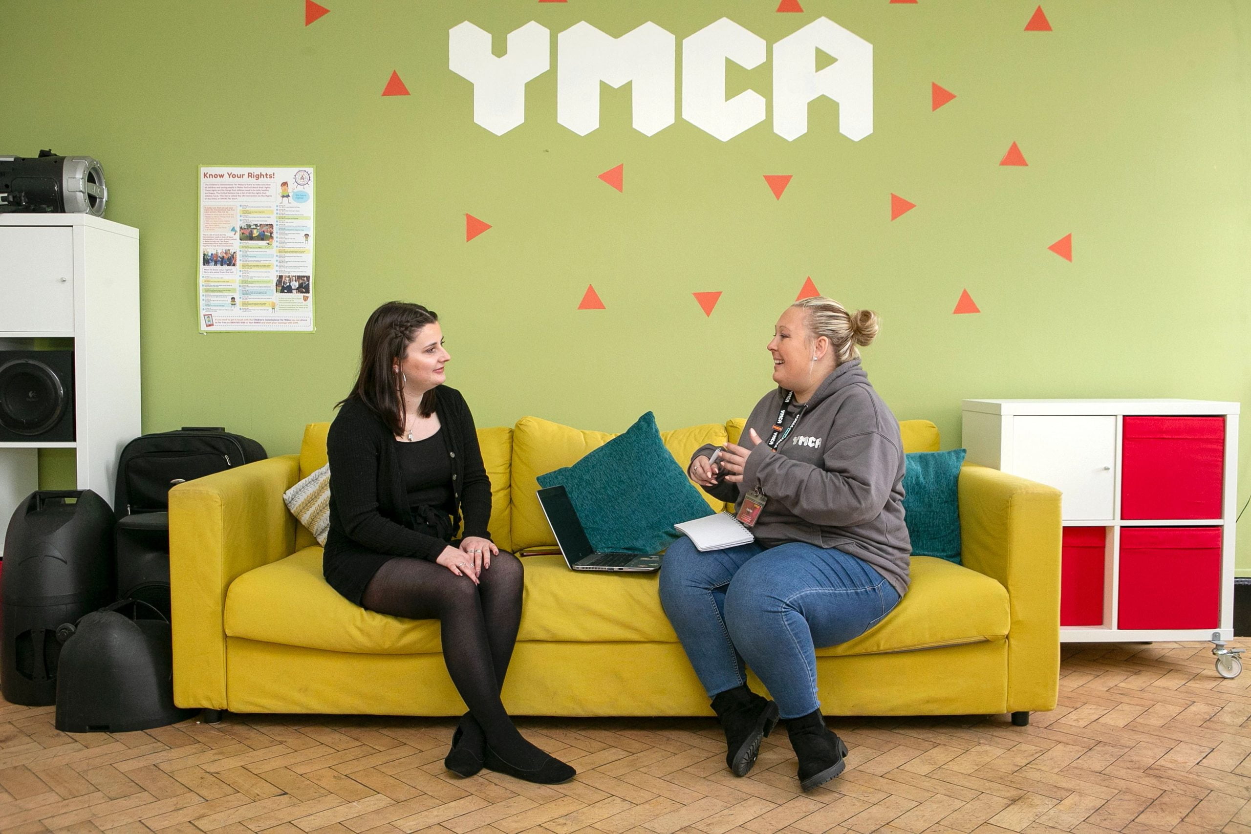 two people talking on a yellow sofa