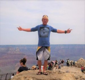 Man, who is now youth worker, on a hill with outstretched arms