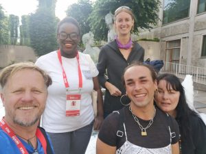 Mapalo and four member of YMCA staff smiling at the camera, each with red lanyards around their neck