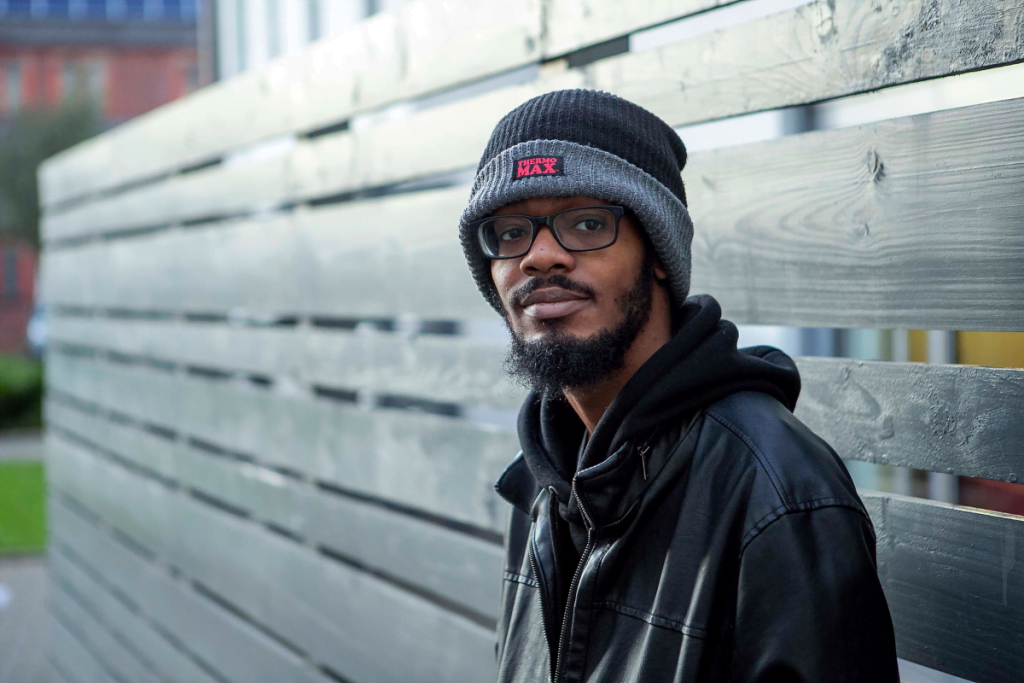 myth busting: young man wearing black coat and winter hat sat on a wooden bench