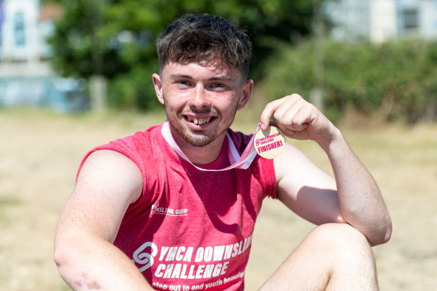 Josh smiling and holding up his medal after completing the DownsLink Challenge