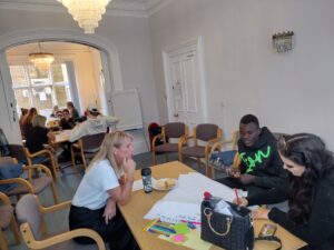 Two members of the Youth Council discussing topics with Jane from the Inspire Team. Sat around a table