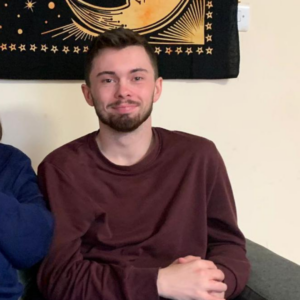 Josh, one of the young people who lived in our supported houses, he is sat on the sofa smiling.