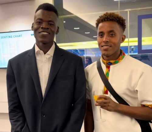 Nader left, smiling in his blue suit. Temesgen, right, smiling holding up a glass of fizzy elderflower