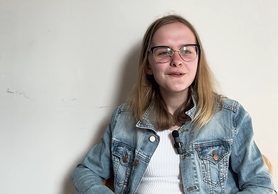Emi, e-wellbeing Youth Mental Health champion smiling, waring a denim jacket and white t-shirt