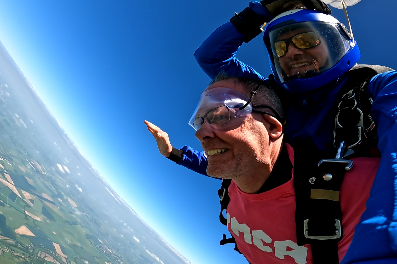 Two men doing a tandem skydive, both are falling through the sky with their arms stretched out to the side.