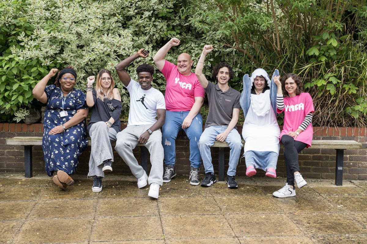 group of people sat on a bench holding their fists up