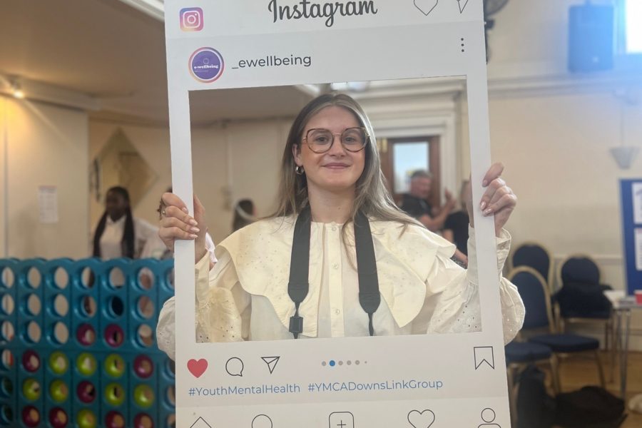 tabs, volunteer photographer, holds a board up that looks like an instagram post and is smiling