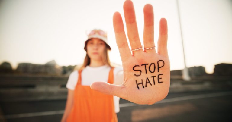 girl holding her hand out. on hand is written stop hate.