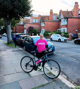 woman with a bike in YMCA top about to take on challenge