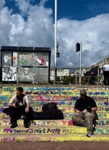 two young men sat of graffiti-covered steps outside