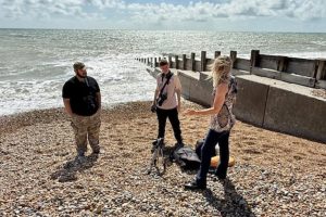 3 people stood on the beach talking