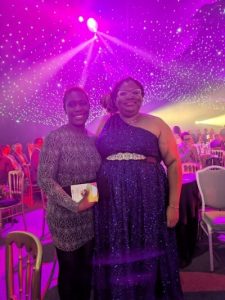 two women dressed in evening attire in a lit up marquee