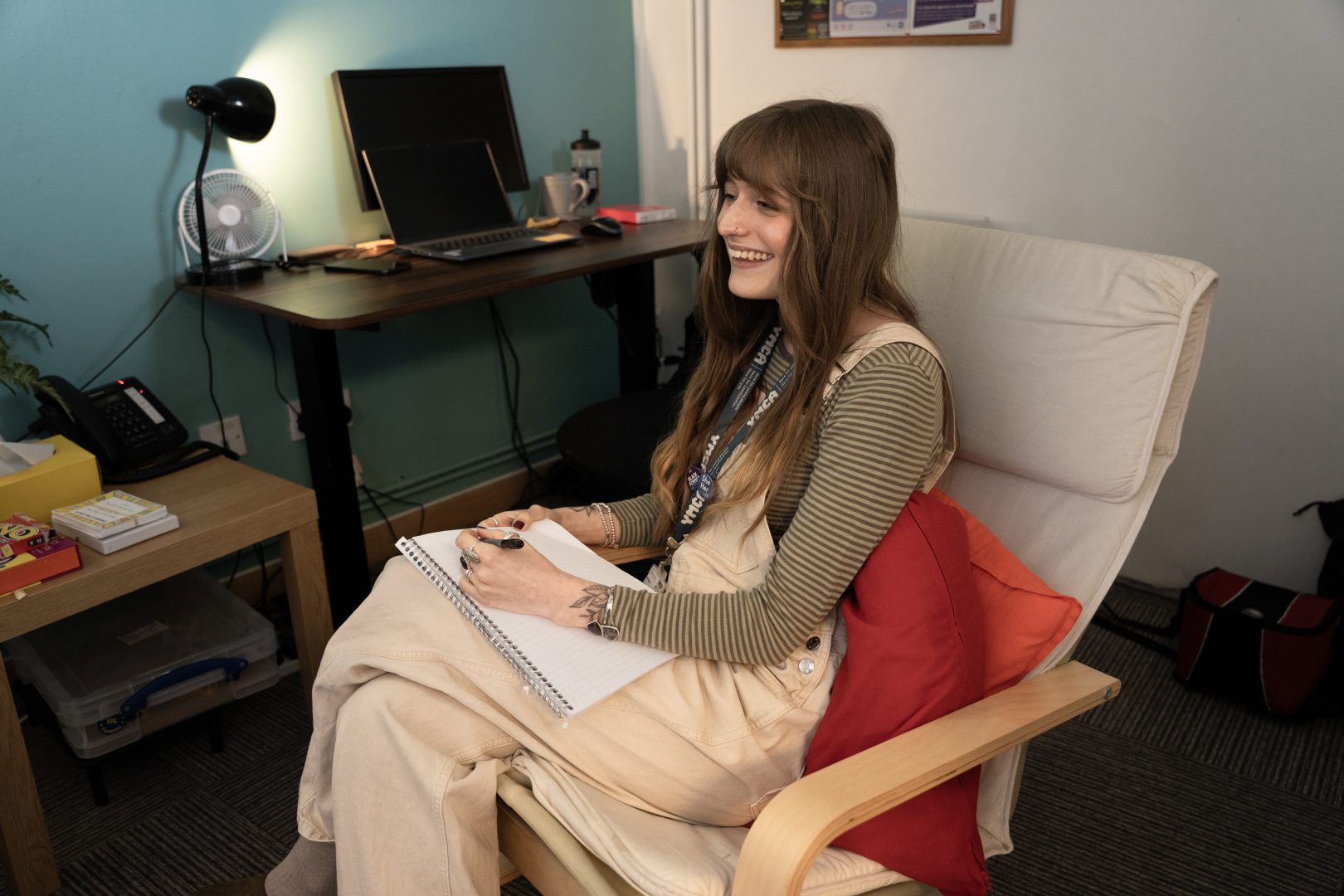 A counsellor sits smiling and taking notes with a student in a session