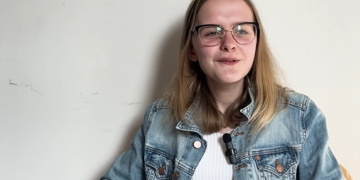 Emi, e-wellbeing Youth Mental Health champion smiling, waring a denim jacket and white t-shirt