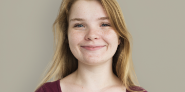 Stacy, a teenage girl with blonde hair smiling, wearing a red top.