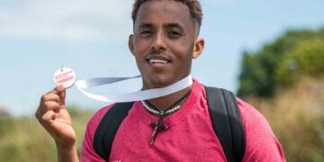 Temesgen smiling holding his medal at the end of the DownsLink Challenge