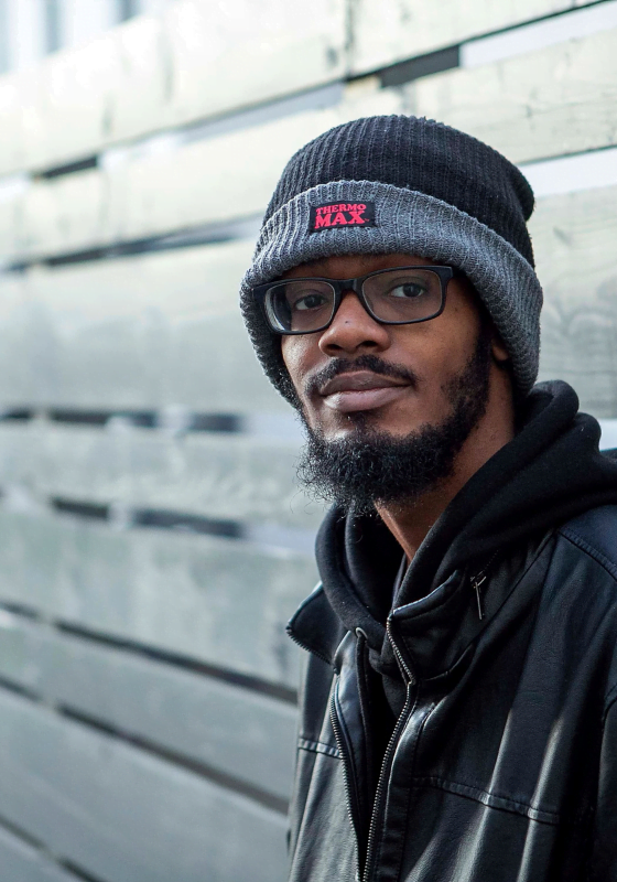 myth busting: young man wearing black coat and winter hat sat on a wooden bench